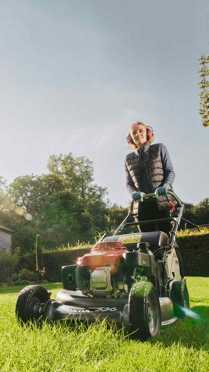Man duwt HRH grasmaaier in tuinomgeving.
