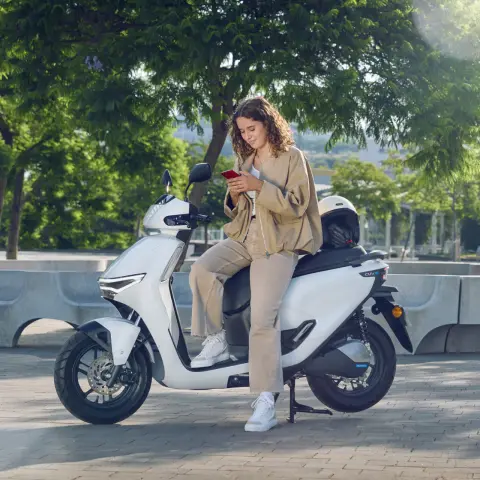 Model leunend op de Honda CUV e motorfiets in een stedelijke omgeving.