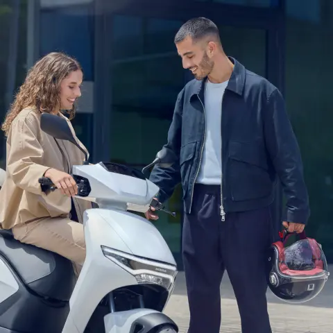 Modellen bestuderen de Honda CUV e-motorfiets in een stedelijke omgeving.